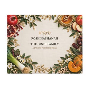 May include: A rectangular placemat featuring a cream-colored center with the text "ROSH HASHANAH THE GINDI FAMILY A TABLE OF SWEET BEGINNINGS" and Hebrew script. The border is decorated with pomegranates, apples, honey, leeks, and pumpkin.