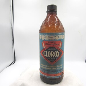 May include: An antique Clorox bottle with a brown glass body and a black cap. The label is blue and red with white text, including "CLOROX" in a diamond shape. The bottle is a vintage cleaning product.