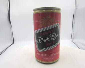 Könnte beinhalten: Eine Vintage-Bierdose von Carling Black Label. Die Dose ist rot mit einem schwarz-weißen Etikett mit der Aufschrift "Carling Black Label Beer". Die Dose trägt auch den Text "America's Lusty, Lively Beer" und "Inhalt 355 ml."