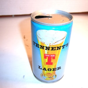 May include: A silver can of Tennent's Lager beer with a blue background and a glass of beer with a white head on the front. The can has the text "Tennent's" in black and "Trade Mark T Lager" in red and black.