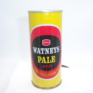 May include: A vintage Watneys Pale Ale can. The can is yellow with a red and black oval label. The label features the Watneys logo and the words "PALE ALE".