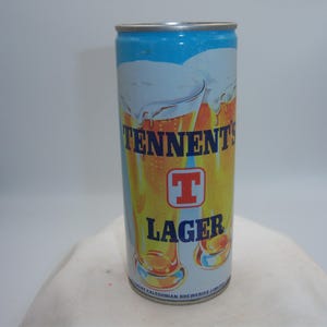May include: A cylindrical Tennent's Lager beer can. The can features a blue top, a white and yellow background with images of beer glasses, and the words "TENNENT'S LAGER" in blue and orange. A red "T" logo is also visible.