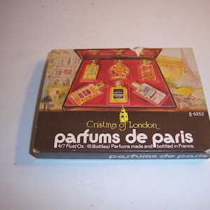 May include: A vintage box set of six perfumes, "Cristina of London, parfums de paris." The box is brown with a red interior, showcasing various perfume bottles. The box reads "4/7 Fluid Oz. (6 Bottles) Parfums made and bottled in France."