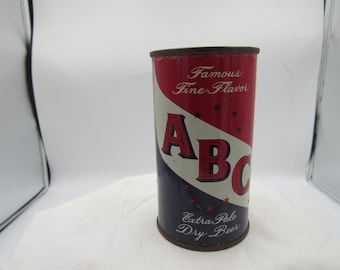 Könnte beinhalten: Vintage ABC Extra Pale Dry Beer Dose. Die Dose hat ein rot-weiß-blaues Farbschema mit den Worten "Famous Fine Flavor" und "ABC" in fetter Schrift. Die Dose hat einen dunkelbraunen Rand und Boden.
