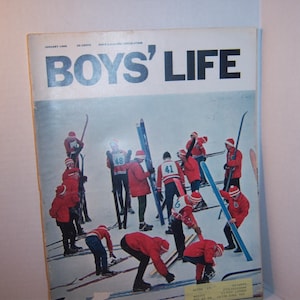 May include: The cover of Boys' Life magazine, January 1966, features a group of skiers in red jackets and hats on a snowy slope. The magazine's title is in large blue letters. Ski equipment is visible.
