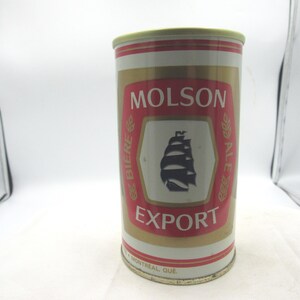 May include: A vintage Molson Export beer can. The can features a red and gold label with the Molson logo, a ship illustration, and the words "EXPORT" and "BIERE ALE". The can is cylindrical and has a gold-colored top and bottom.