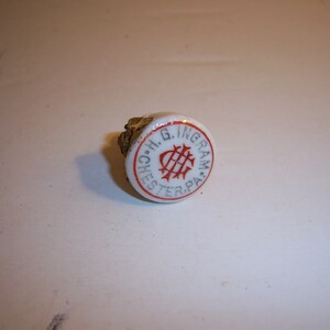 May include: White ceramic bottle stopper with a red and blue logo that reads "H.G. Ingram, Chester, PA".