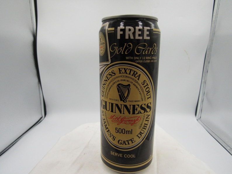 May include: A black Guinness Extra Stout beer can with gold accents. The can features the Guinness logo, a harp, and the text "500ml". The can also has the text "FREE Gold Cards".
