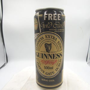 May include: A black and gold Guinness Extra Stout can with the text "FREE Gold Cards" at the top. The can features a gold label with the Guinness logo, a harp, and the text "500ml".