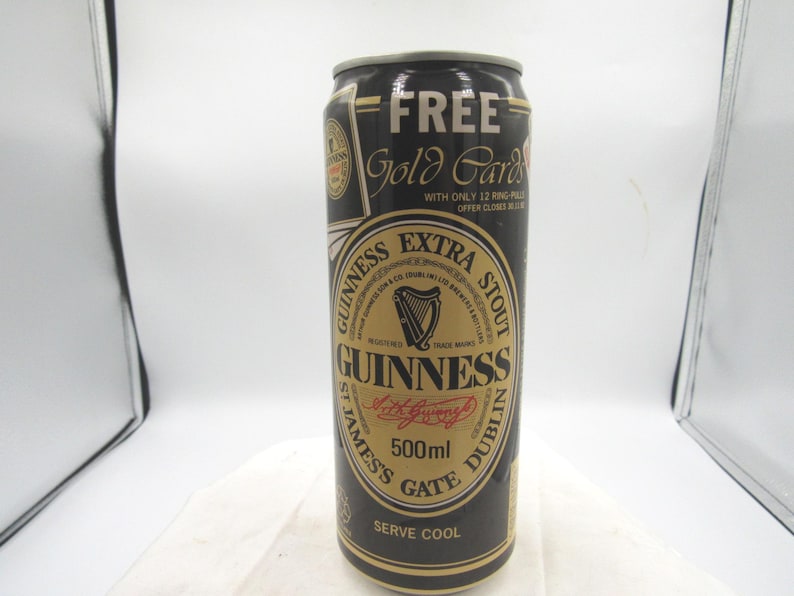 May include: A black and gold Guinness Extra Stout can with the text "FREE Gold Cards" at the top. The can features a gold label with the Guinness logo, a harp, and the text "500ml".