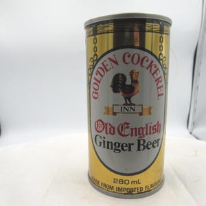 May include: Vintage Golden Cockerel Inn Old English Ginger Beer can. The can has a gold and silver color scheme with a rooster logo. The can contains 280 mL of ginger beer and is made from imported flavors.