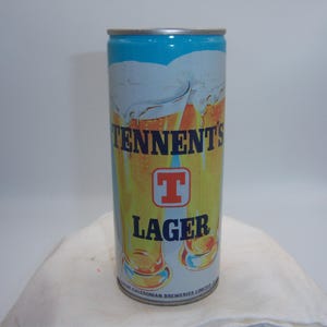 May include: A cylindrical Tennent's Lager beer can. The can features a blue top, a white and yellow body with the brand name and logo, and a silver rim. The can is standing upright.