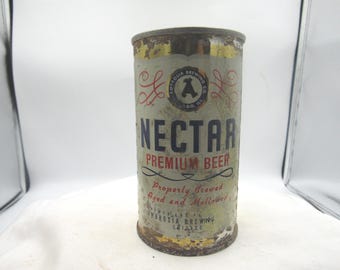 May include: Vintage Nectar Premium Beer can. The cylindrical can has a faded, aged appearance with a light green and gold color scheme. The text "Nectar Premium Beer" is prominently displayed, along with the Ambrosia Brewing Co. logo.