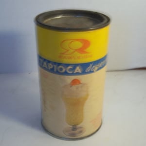 May include: A yellow and blue can of Rawleigh's Tapioca dessert mix. The can has a picture of a glass of tapioca pudding with a cherry on top.