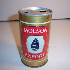 May include: A gold aluminum can of Molson Export beer. The can has a red and white label with the words "Molson Export" and a blue ship logo. The can also has the words "Brewers Since 1786" printed on it.