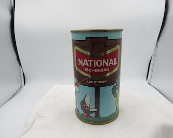 May include: A vintage National Bohemian Light Beer can. The can has a red and gold label with the words "NATIONAL BOHEMIAN LIGHT BEER". The can features cartoon illustrations of a crab and a turtle. The can is cylindrical and made of metal.
