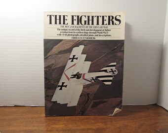 May include: A book titled "The Fighters: The Men and Machines of the First Air War" by Thomas I. Funderburk. The cover features a black and white photograph of a World War I era German fighter plane with red markings.