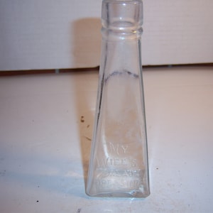 May include: A clear glass bottle with a triangular shape and a label that reads "My Wife's Dressing".