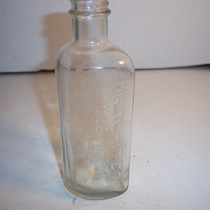 May include: Clear glass bottle with a rounded body and a narrow neck. The bottle has embossed text that reads "DR. WHITE'S LUNG-CE." The bottle is empty and appears to be vintage.