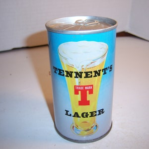 May include: A blue and silver aluminum can with a picture of a glass of beer with a white head. The can says "Tennent's Trade Mark T Lager" in black letters.