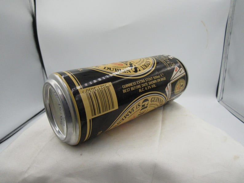 May include: A black and gold Guinness Extra Stout 500ml can, with text including "Dublin" and "St. James". The can has a silver top and base, and the label includes the text "Best Before Date Shown on Base ALC. 4.3% VOL".