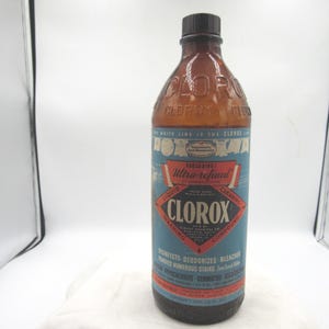 May include: A vintage Clorox liquid cleaning compound bottle. The brown glass bottle has a black cap and a blue and red label with the brand name and product information. The label reads "Ultra-refined" and "Disinfects - Deodorizes - Bleaches".