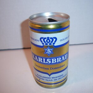 May include: A gold can of Karlsbrau German Dosenbier with a blue and white label featuring a crown and a star. The label also includes the text "Goldbrau" and "Deutsches Dosenbier".