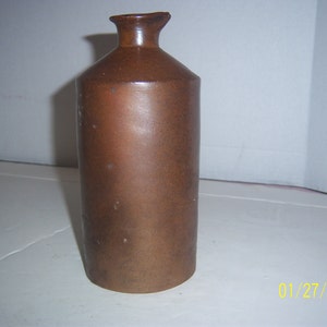 May include: A brown ceramic ink bottle with a rounded top and a slightly flared base.