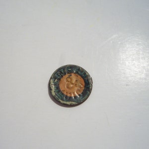 May include: A round, blue and white metal token with the words "Five Cents" and a small image of a person in the center.