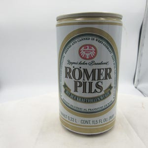 May include: A vintage Romer Pils beer can. The can is white with gold and green accents, and features the brand name and text in German. The can contains 11.5 fl oz (0.33 L) of beer.