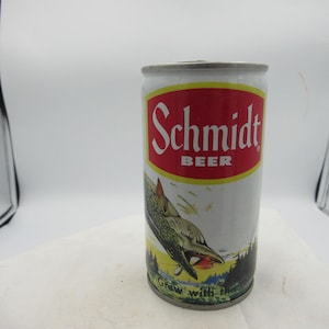 May include: A vintage Schmidt Beer can. The can is white with a red and yellow label. The label features the word "Schmidt" in white, and the word "BEER" in yellow. A fish graphic is on the can.