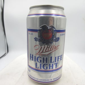 May include: A silver Miller High Life Light beer can. The can features a blue and red design with the words "Miller High Life Light" in large letters. The can also has the text "12 fl oz" and "Contains no additives or preservatives."