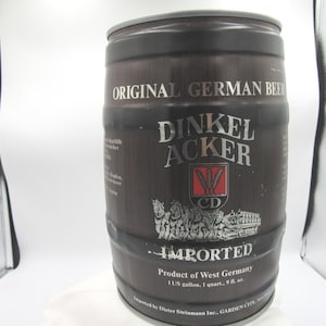 May include: A dark brown beer keg with silver lettering that reads "ORIGINAL GERMAN BEER" and "DINKEL ACKER". The keg also has a logo and the word "IMPORTED". The product is from West Germany and holds 1 US gallon.