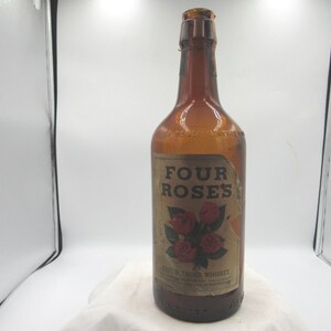 May include: An amber-colored glass bottle with a label that reads "FOUR ROSES" and features a graphic of red roses. The bottle is filled with a liquid and has a dark brown cap. The label also says "FINE BLENDED WHISKEY".