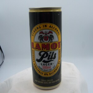 May include: A black and gold Lamot Pils Lager beer can. The can has a yellow and white label with the text "LAMOT Pils" and "500ml". The can is 6% alcohol by volume.