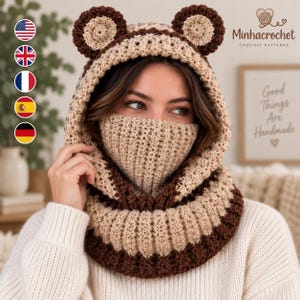 May include: A beige and dark brown crochet balaclava featuring two rounded bear ears on top. The head covering includes an integrated face mask section and a ribbed neck warmer, crafted with a textured yarn pattern in alternating color bands.