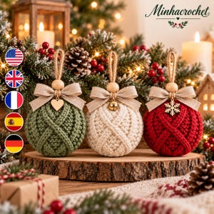 May include: Three round crochet Christmas ornaments in sage green, cream, and red. Each features a textured cable knit pattern, a beige linen bow, a wooden bead, and a jute hanging loop. The ornaments are adorned with a heart, a bell, and a snowflake.