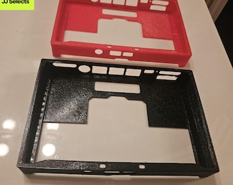 May include: Two rectangular protective cases for an electronic device, one in bright red and one in black. Both cases feature a textured finish and multiple precise cutouts along the edges for ports and buttons, with a large central opening.