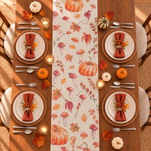 May include: A beige table runner featuring a repeating pattern of orange pumpkins, various mushrooms, and autumn leaves in shades of red, orange, and yellow. The runner is centered on a wooden table set with four place settings.