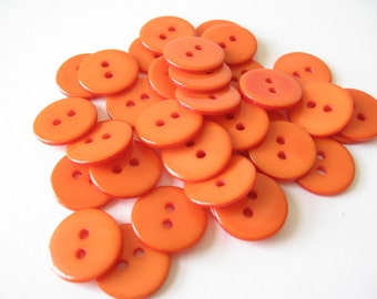 May include: A pile of orange plastic buttons with two holes each.