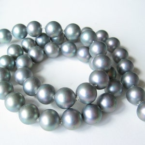 May include: A strand of iridescent gray pearls, strung together on a silver thread. The pearls are round and smooth, with a subtle shimmer.