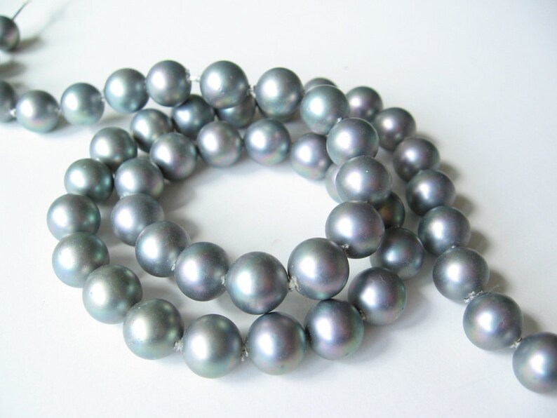 May include: A strand of iridescent gray pearls, strung together on a silver thread. The pearls are round and smooth, with a subtle shimmer.