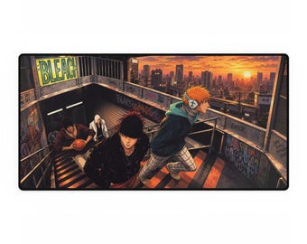 May include: A rectangular desk mat featuring an anime illustration of three characters descending a concrete staircase at sunset. The scene includes graffiti-covered walls, a city skyline in the background, and the word BLEACH on a yellow sign.