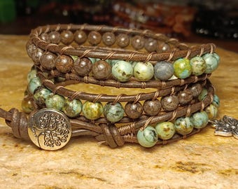May include: A brown leather wrap bracelet with turquoise and brown beads. The bracelet features a tree of life charm and a butterfly charm.