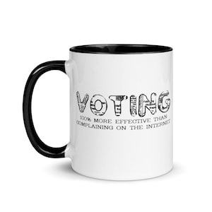 Peut inclure: Un mug en céramique blanche avec une anse et un bord intérieur noirs. L'avant présente le mot VOTING dans une police de style journal, suivi du texte 100% MORE EFFECTIVE THAN COMPLAINING ON THE INTERNET dans une police serif noire plus petite.