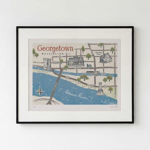 May include: A framed art print featuring a stylized map of Georgetown, Washington, D.C. The map displays the Potomac River in blue, street grids, and landmarks like the Old Stone House and C&O Canal. Text includes Georgetown, Washington, D.C.