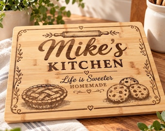 Puede incluir: Una tabla de cortar rectangular de bambú con un diseño grabado a láser que incluye el texto Mike's KITCHEN, Life is Sweeter HOMEMADE, una ilustración de un rodillo, un pastel y tres galletas con chispas de chocolate.