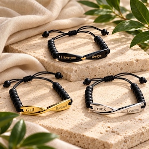 Op de afbeelding: Drie verstelbare armbanden met zwarte kralen en een centrale gedraaide metalen staaf. Een zwarte staaf is gegraveerd met "I love you always" en een hartje. Een gouden staaf bevat "Gail" en "Richard". Een zilveren staaf bevat "Frank" en "Leanne".