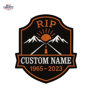 Puede incluir: Un parche bordado en forma de escudo con fondo negro y borde naranja. Presenta el texto RIP, un sol saliendo sobre montañas blancas, una carretera y una pancarta con el texto CUSTOM NAME y los años 1965-2023 en color naranja y blanco.