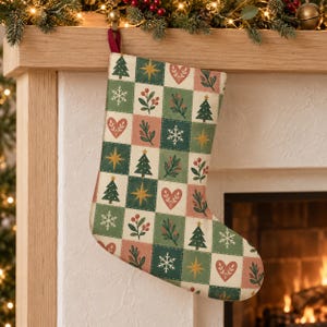 May include: A Christmas stocking featuring a patchwork grid pattern of alternating squares in shades of green, cream, and muted red. The squares display repeating motifs of pine trees, snowflakes, stars, hearts, and sprigs of berries.